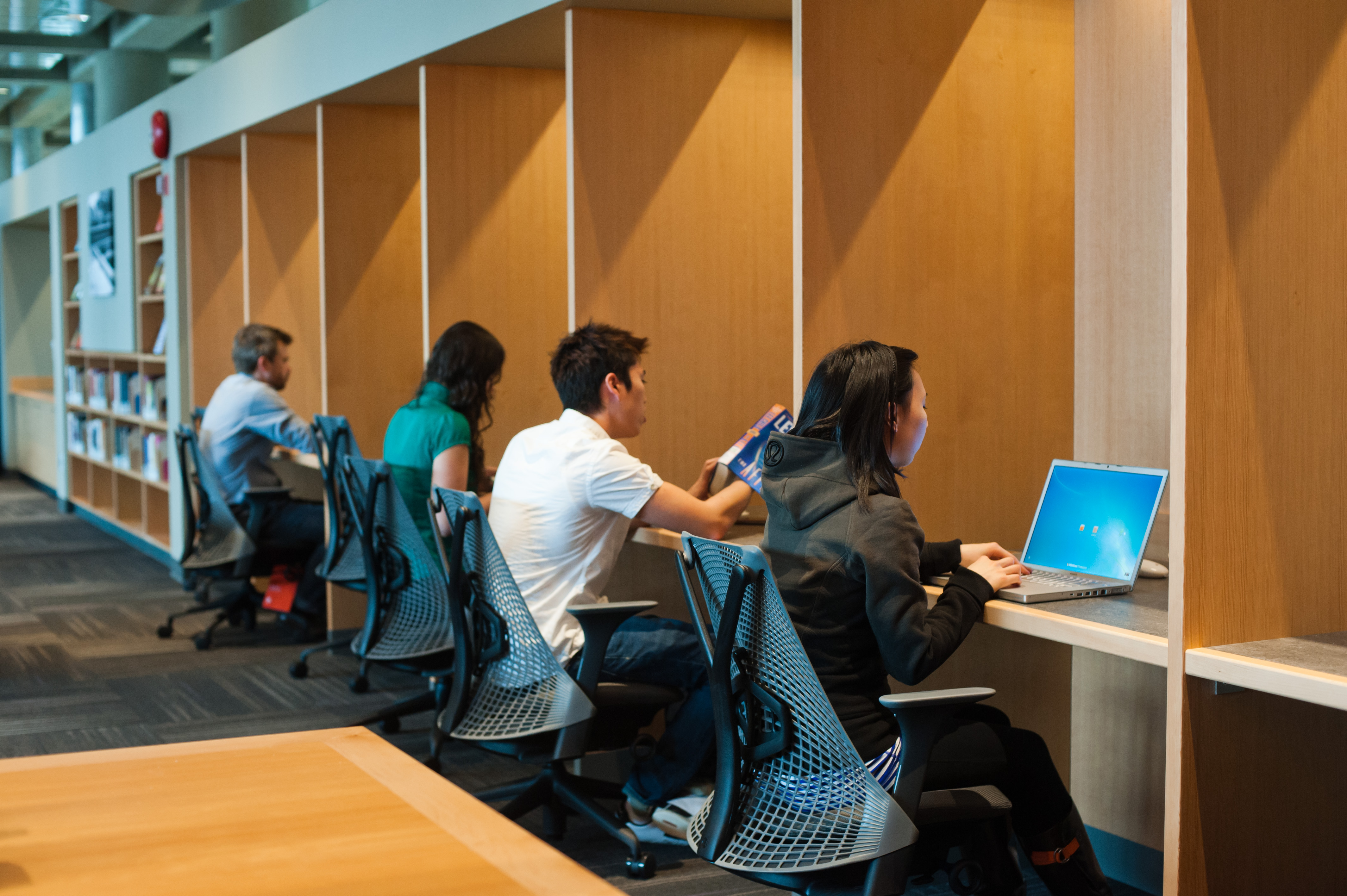 Students with laptops seated at cubicles